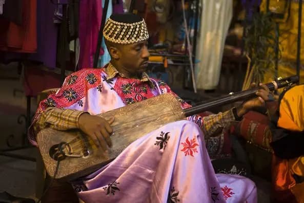 Gnawa au coin de rue qui anime la place de Marrakech